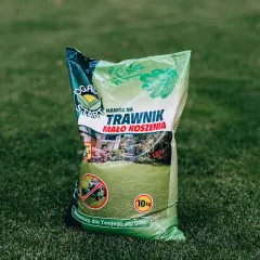Zielona torba z nawozem do trawnika na tle trawy.