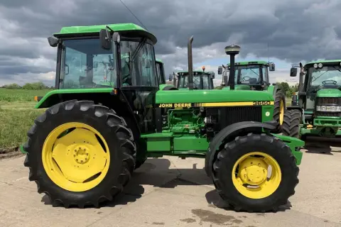 Zielony traktor John Deere 3650 z żółtymi felgami, gotowy do pracy na polu.
