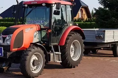 Czerwony traktor Zetor z przyczepą. Zastanawiasz się, ile kosztuje prawo jazdy na traktor?