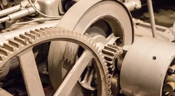 Metalowe koła zębate, w tym duża zwolnica, tworzą skomplikowany mechanizm napędowy.