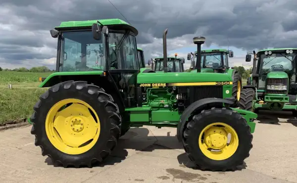 Zielony traktor John Deere 3650 z żółtymi felgami, gotowy do pracy na polu.