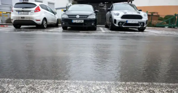 Trzy samochody zaparkowane na mokrym, błyszczącym od lodu asfalcie.
