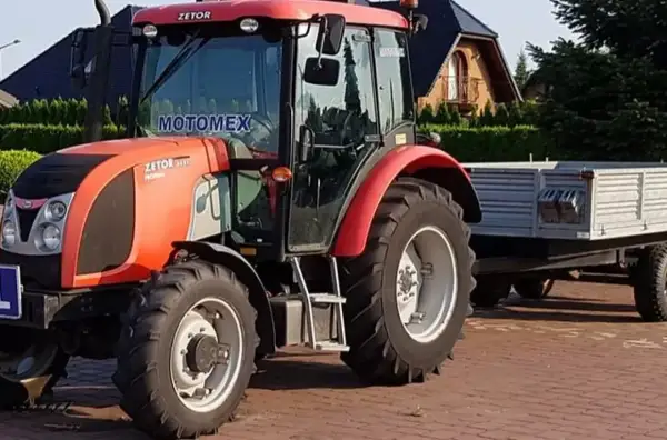 Czerwony traktor Zetor z przyczepą. Zastanawiasz się, ile kosztuje prawo jazdy na traktor?